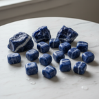 Sodalite raw and tumblestone crystals on light background